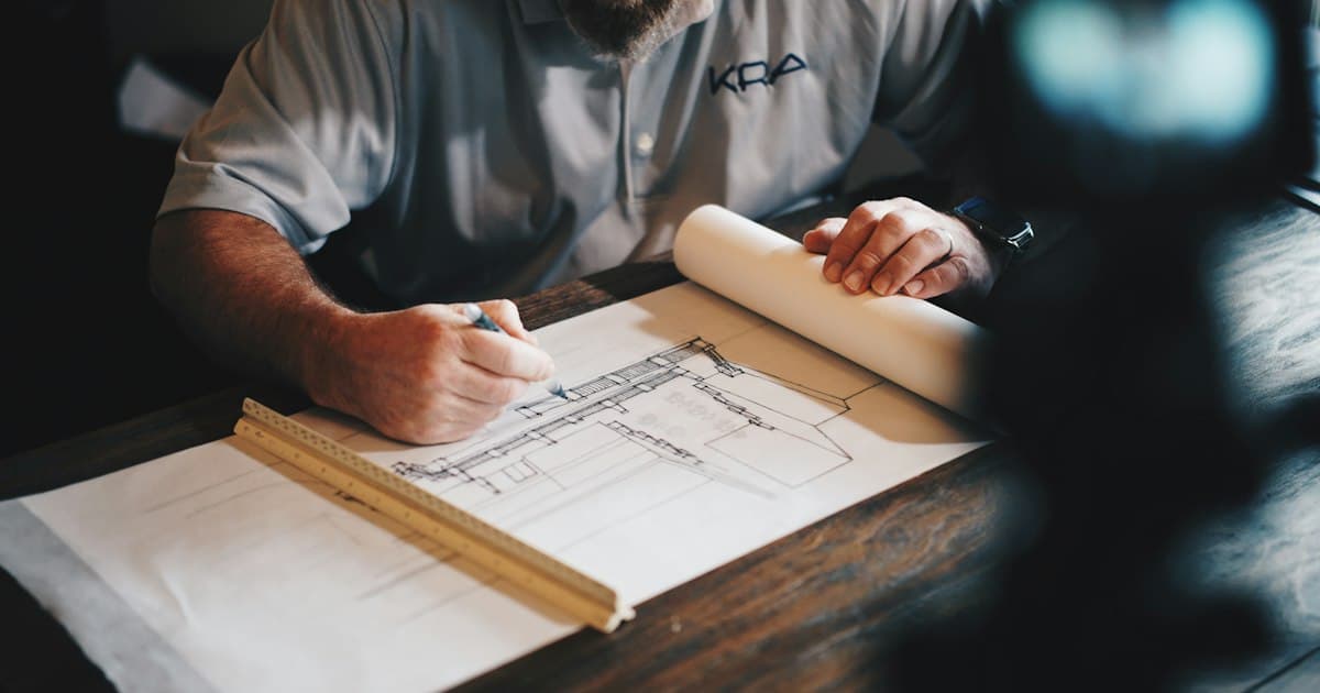 Personne dessinant des plans sur une table de travail