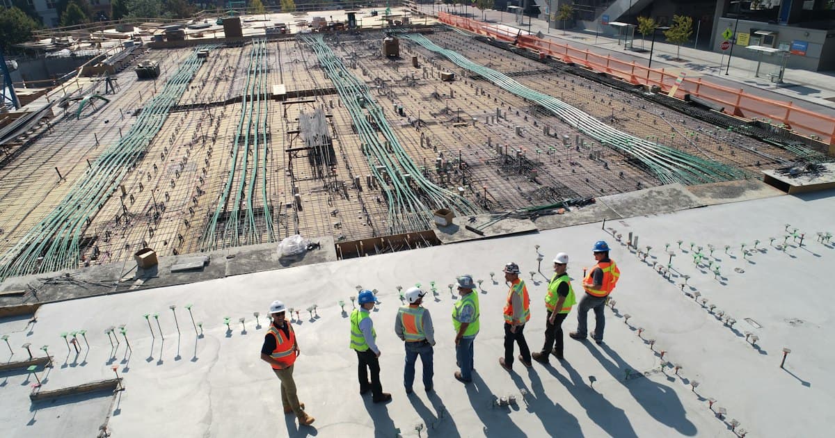 Personnes portant des casques devant un chantier de construction