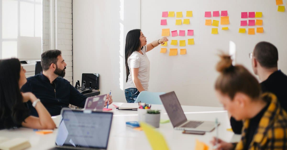 Personnes réunies autour d’une table face à un mur de notes