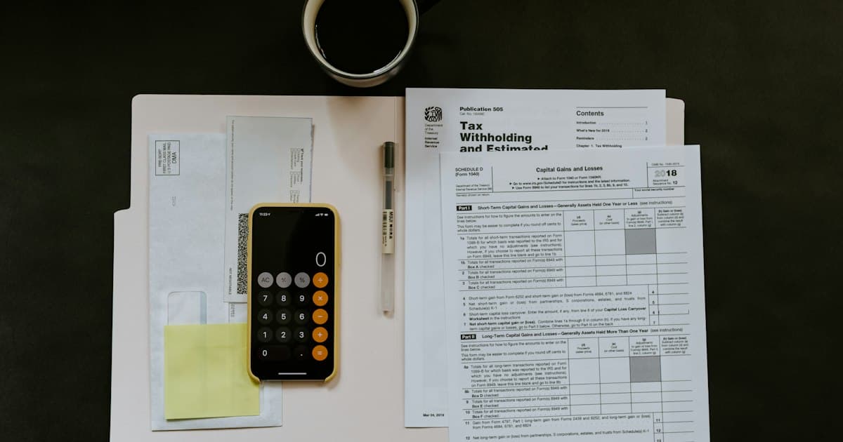 Documents, calculatrice et tasse disposés sur un bureau